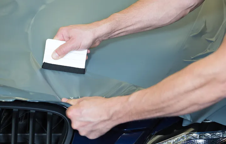 <p>Car wrappers using squeegee to straighten vinyl foil</p>
