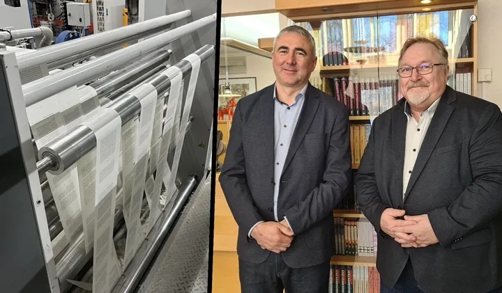 <p>Paulius Juška, vd för Scandbook, tillsammans med Alf Linder som är platschef på Scandbook i Falun. Den breda pappersbanan i digitalpressen skärs upp till sidor innan bokblocken skapas.</p>

