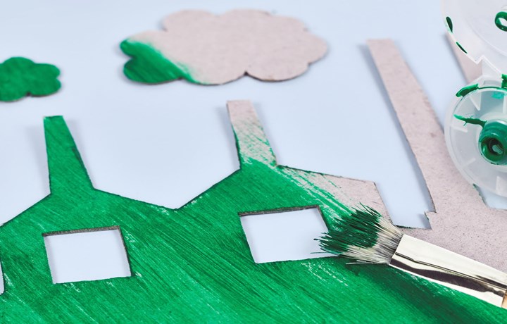 <p>Greenwashing concept with cardboard factory being painted green</p>
